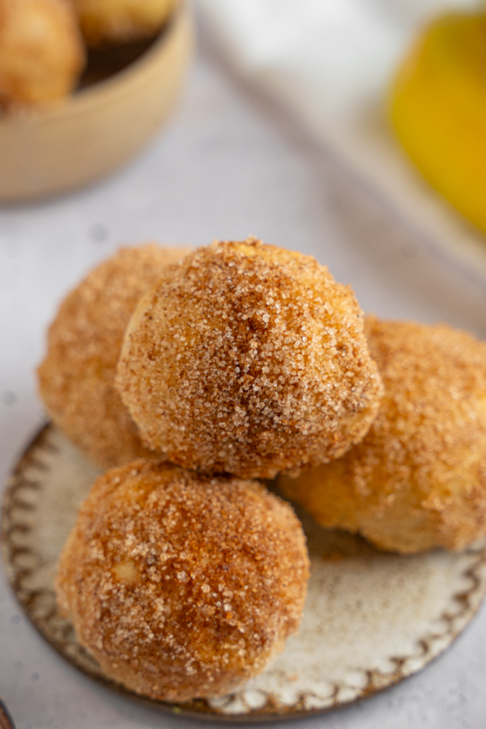 Close up of the banana donut holes stacked on a dessert plate.