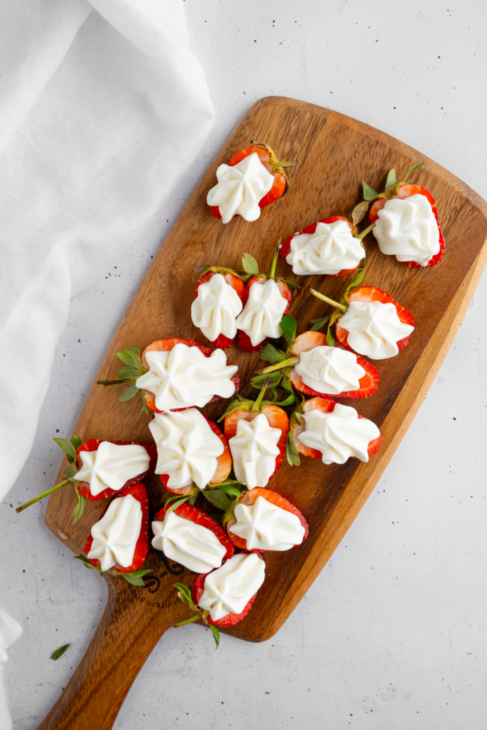 Creamy vegan filling piped into strawberry halves.