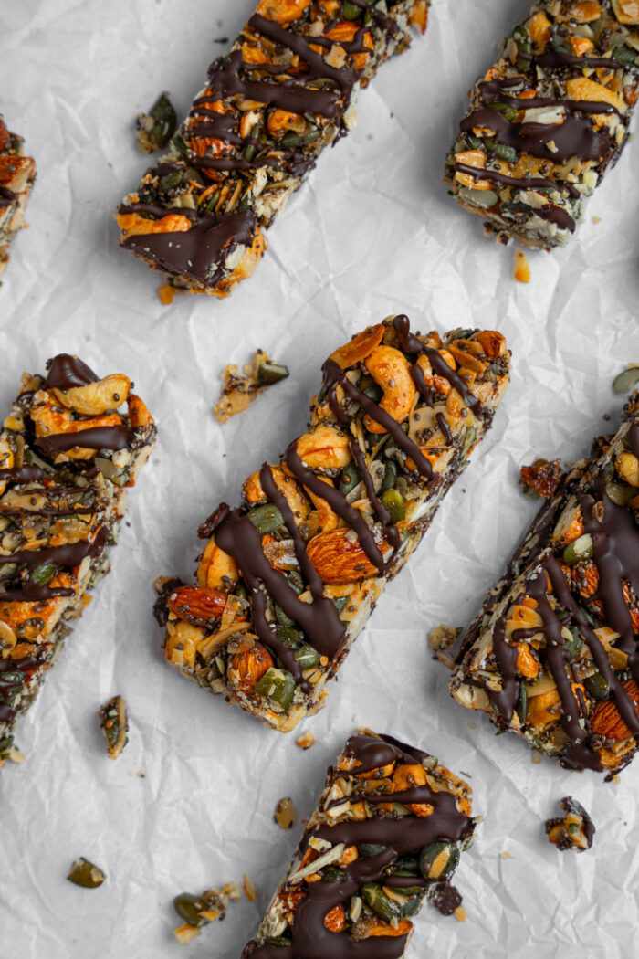 Nut and seed energy bars with chocolate laid out on top of parchment paper.