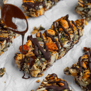 Chocolate being drizzled on top of each nut and seed energy bar.