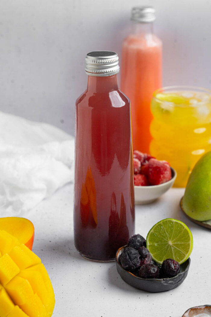Homemade electrolyte drinks of different flavors in glass bottles, with featured ingredients visible in the photo.