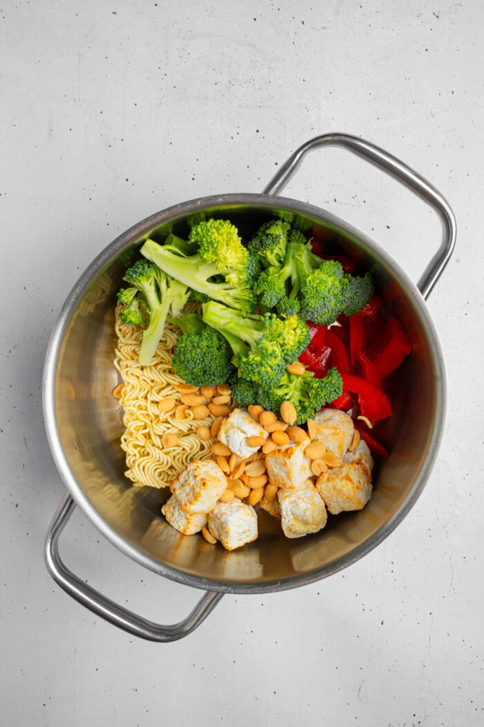 Veggies, noodles and tofu puffs in a steel pot.