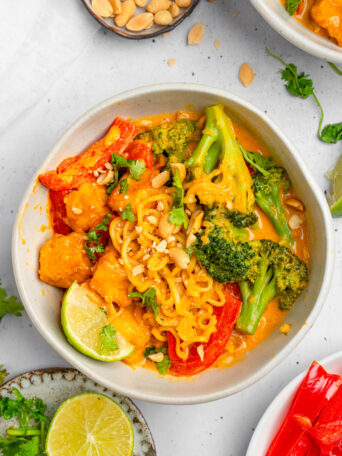 Creamy Thai red curry noodles served in a white ceramic bowl.