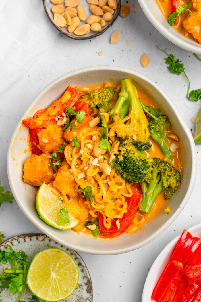 Creamy Thai red curry noodles served in a white ceramic bowl.