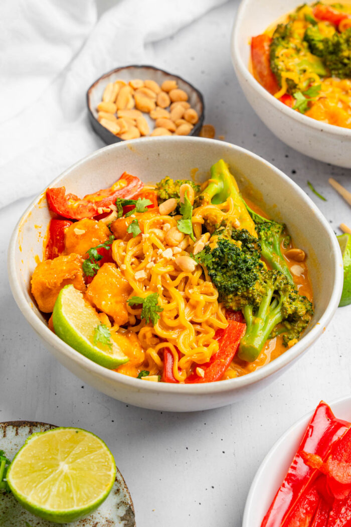 A bowl of one pot creamy Thai red curry noodles, with garnishes visible in the picture.