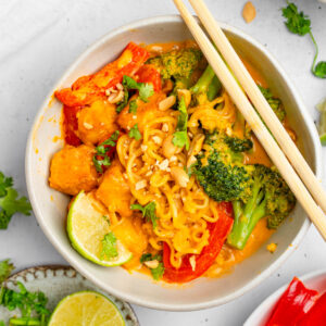 Creamy Thai red curry noodles served in a white ramen bowl with chopsticks resting on the side.
