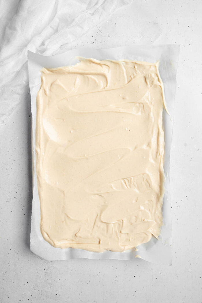 The yogurt and peanut butter mixture spread evenly on a lined baking sheet.