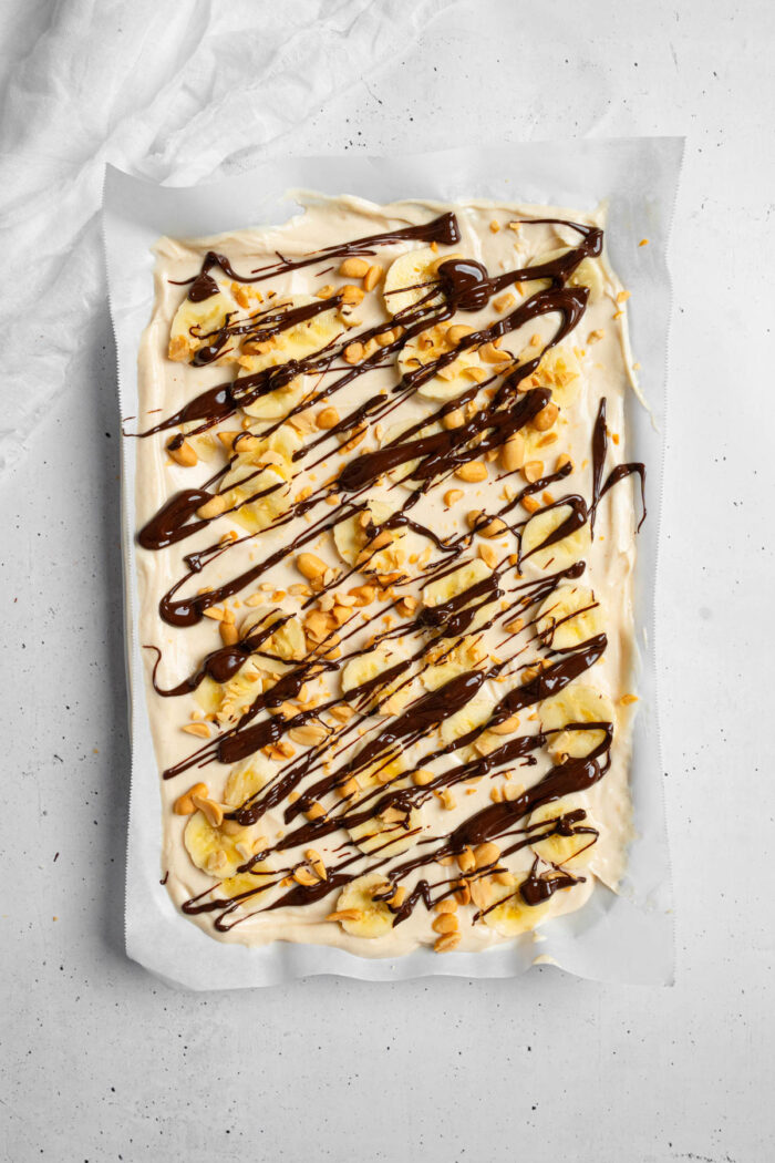 Yogurt and peanut butter mixture drizzled with chocolate, more peanut butter, with bananas and crushed peanuts.