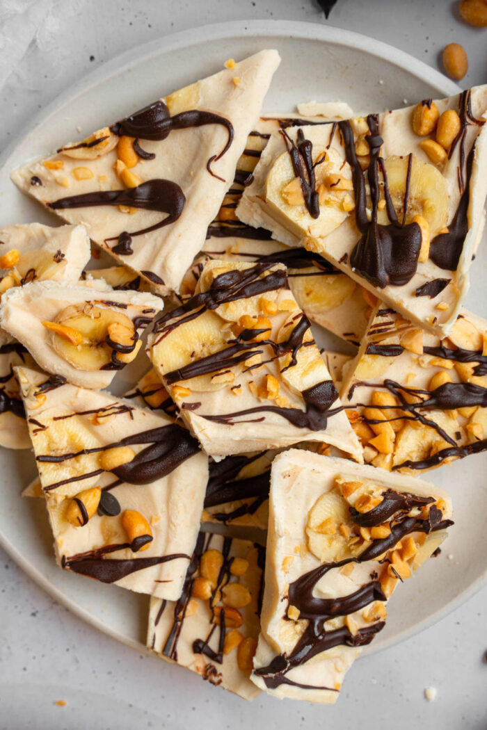 Peanut butter yogurt bark with bananas, crushed peanuts and chocolate drizzle.
