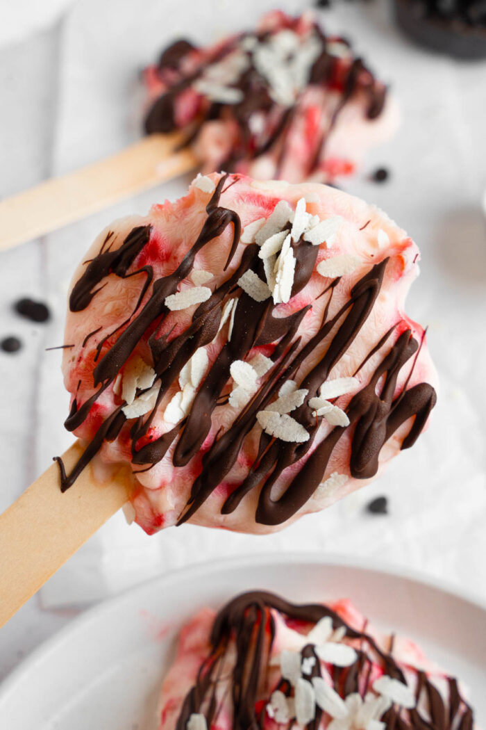 A close up of a ready strawberry yogurt clusters, drizzled with chocolate and sprinkled with coconut.