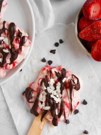 A top down shot pf a strawberry popsicle drizzled with chocolate and sprinkled with coconut.