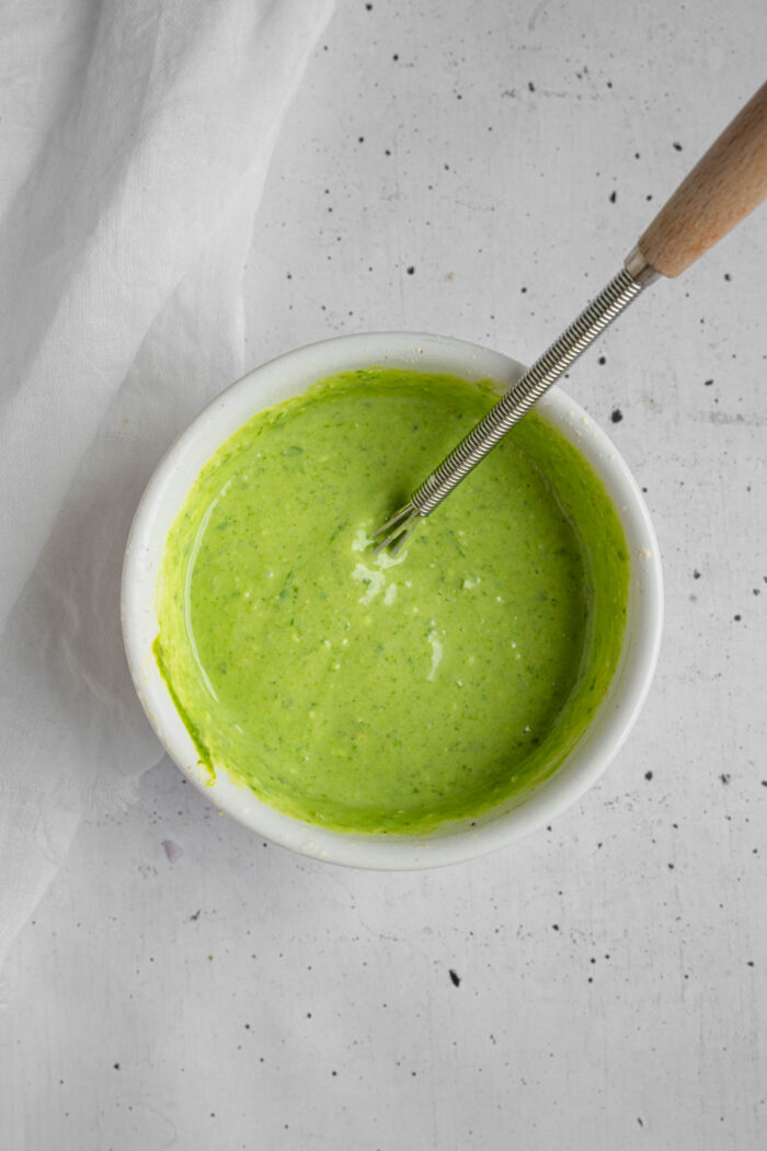Vegan pesto dressing mixed up in a bowl.