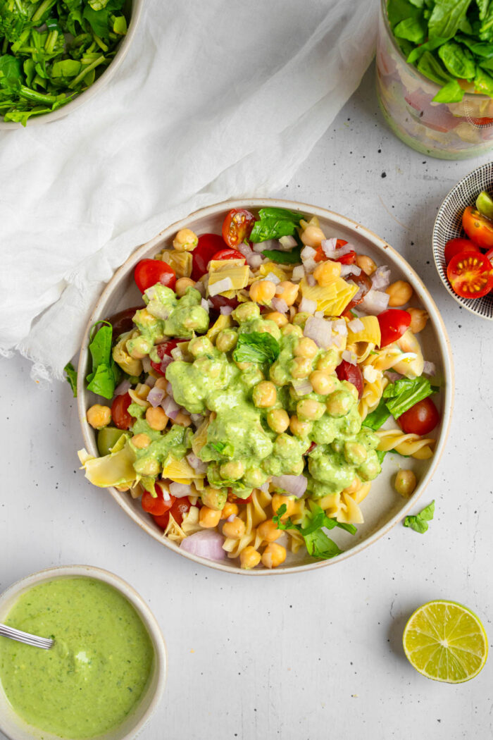 Top view of the pesto pasta salad on a plate, with the dressing all over.