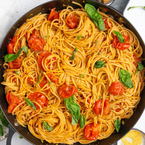 A large skillet photographed from the top, full to the brim of one pot chery tomato basil pasta.