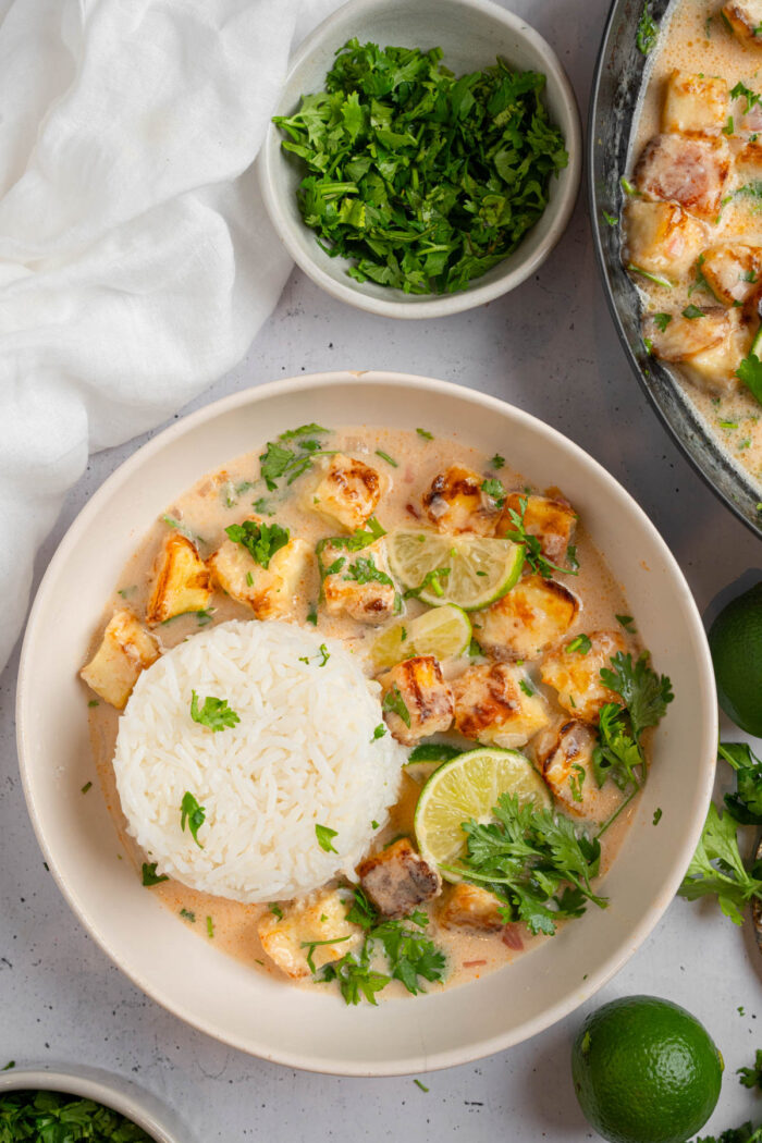 Coconut lime tofu served in a white ceramic bowl with rice and fresh cilantro.