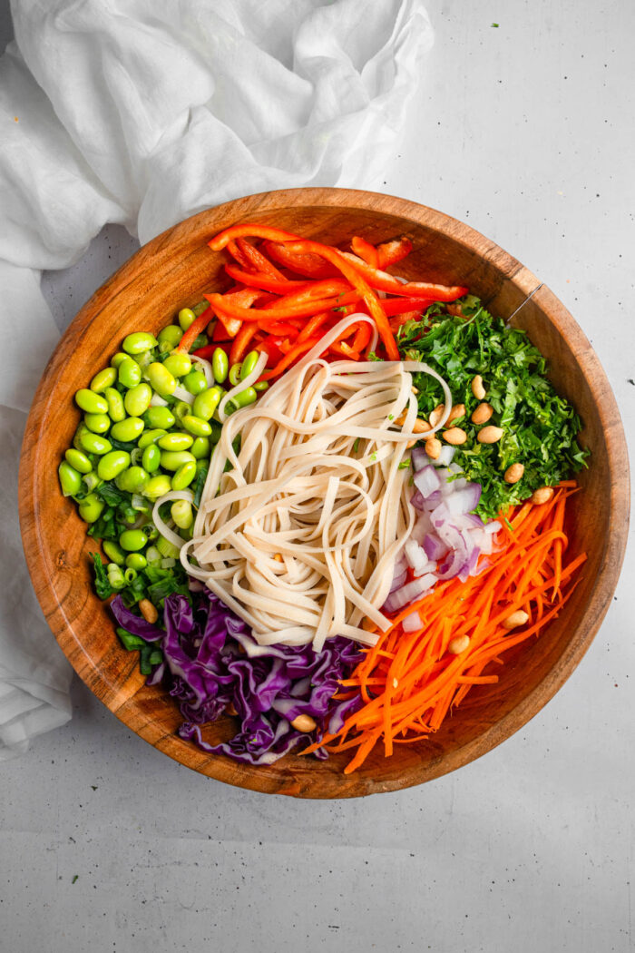 Noodles, edamame, veggies, and greens in a large bowl.