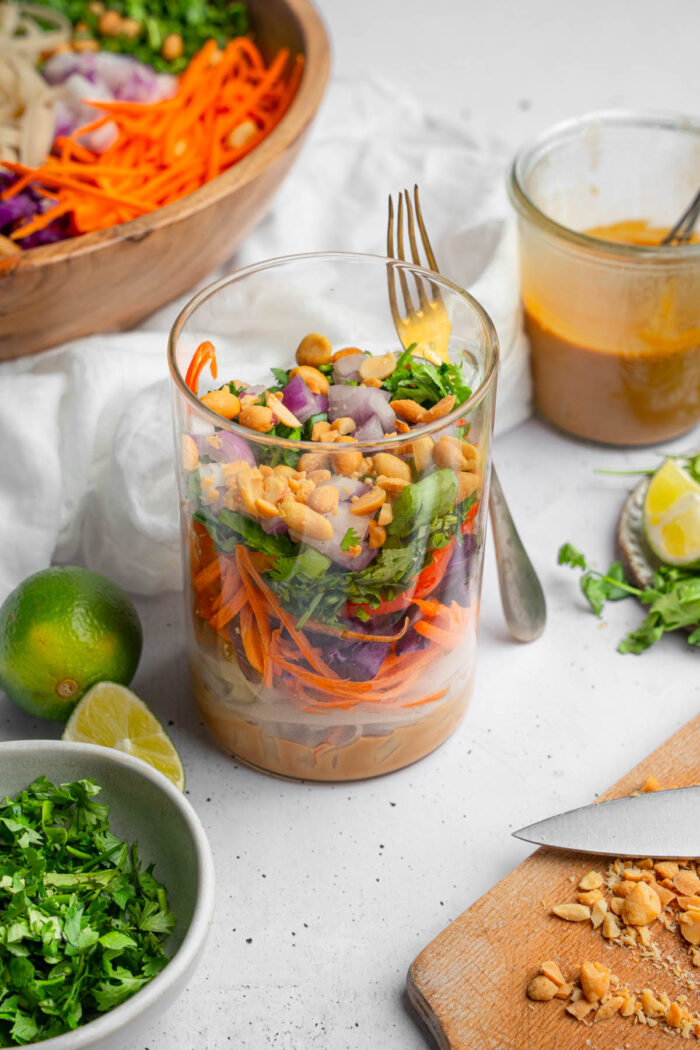 Meal prep version of Thai noodle salad in a jar, with ingredients over the peanut dressing.