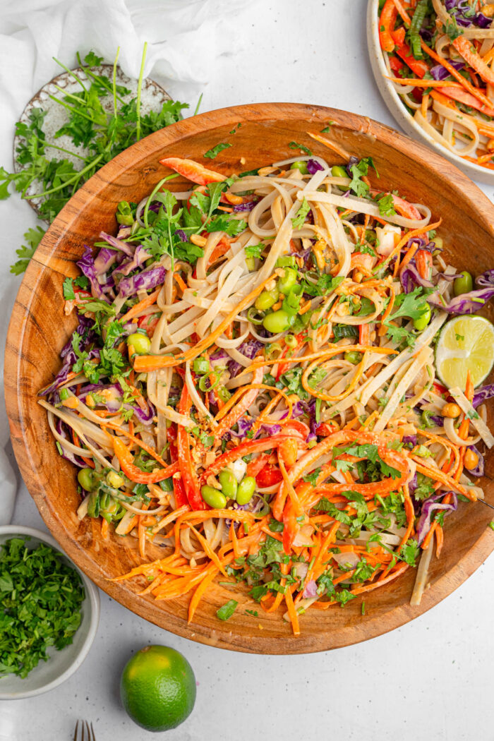 Thai noodle salad stirred together in a large wooden salad bowl.