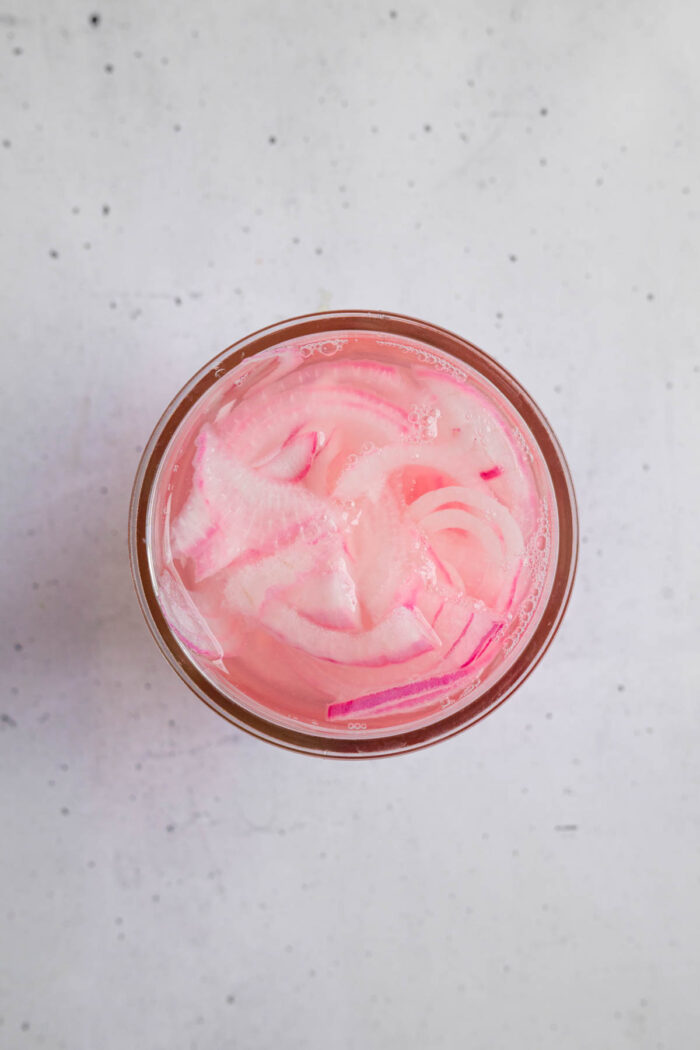 Top down photograph of quick pickled onions in a glass.