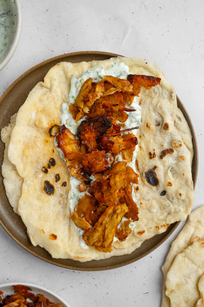 Marinated tofu on top of vegan tzatziki inside of a heated wrap.