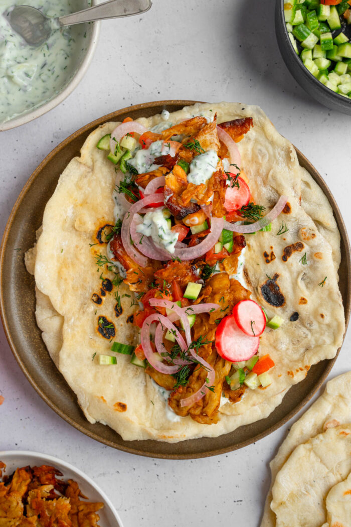 A wrap with all the fillings and vegan tzatziki laid out at the center.