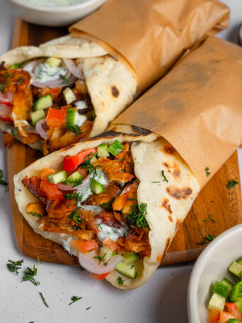 Two vegan shawarma wraps on a cutting board.