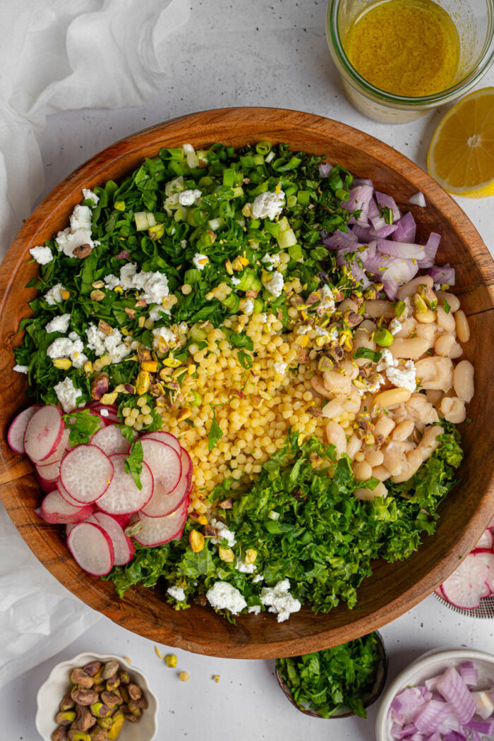 Different ingredients for the kale white bean salad aded to a large salad mixing bowl.