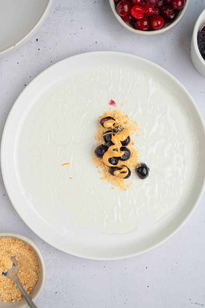 Peanut butter drizzled on top of fresh blueberries to make rice paper dumplings.