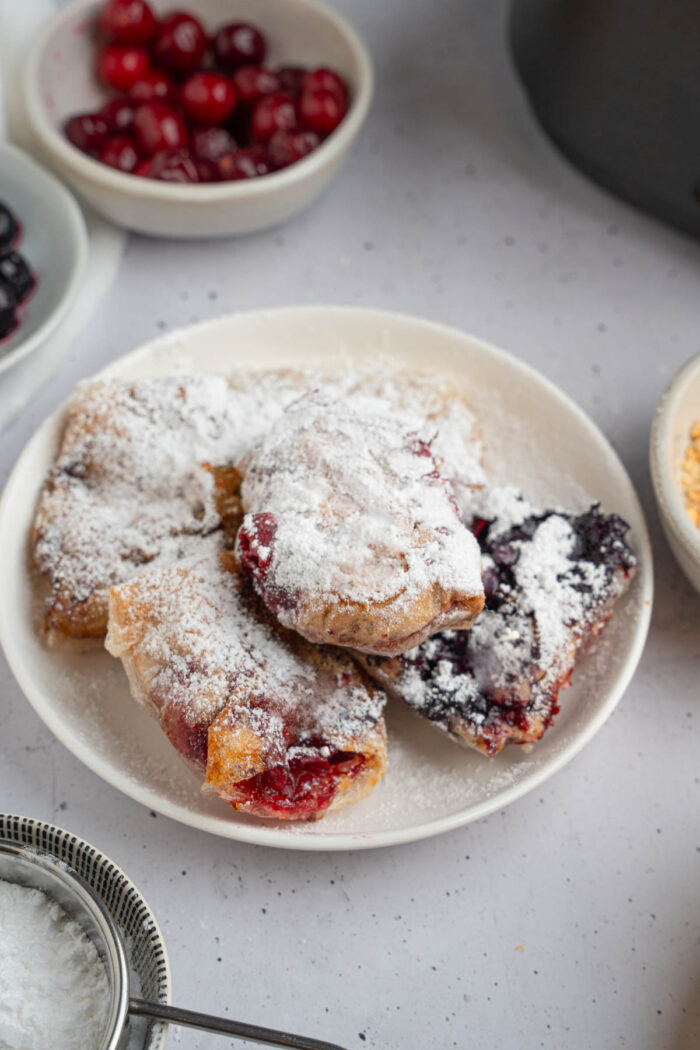 Sweet rice paper dumplings finished with powdered sugar and set on a plate.