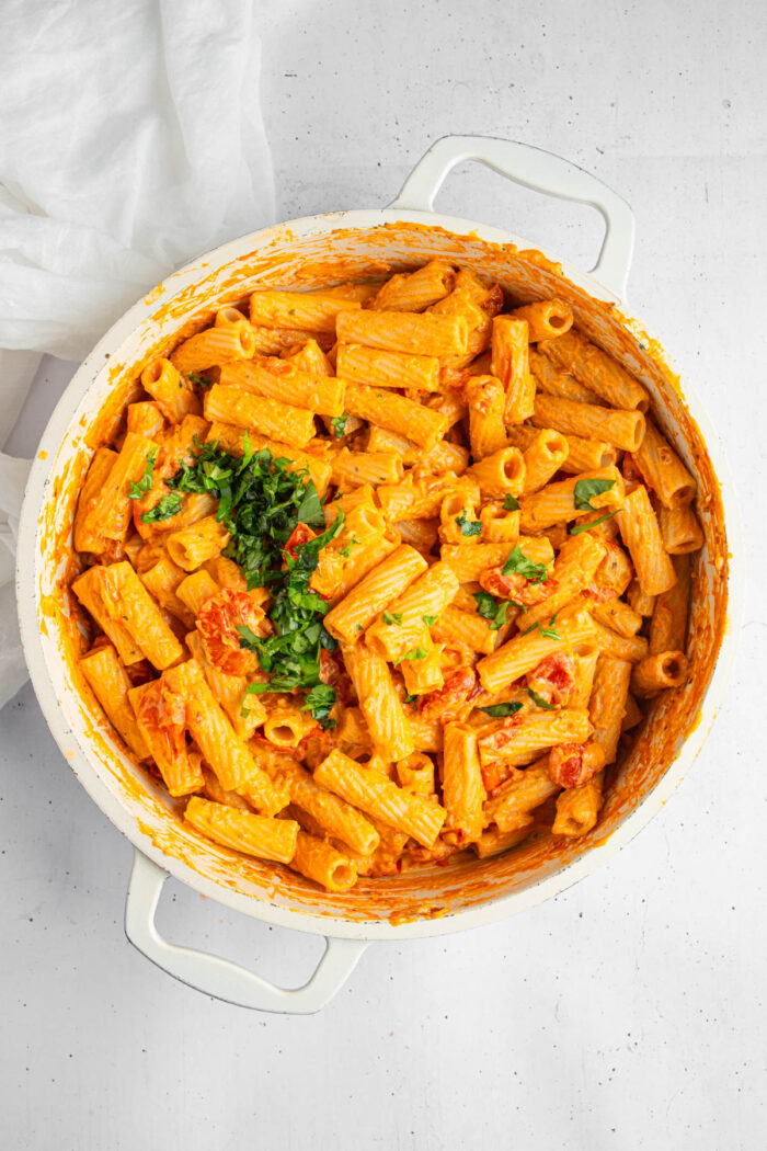 Rigatoni and basil added to the creamy tomato sauce.