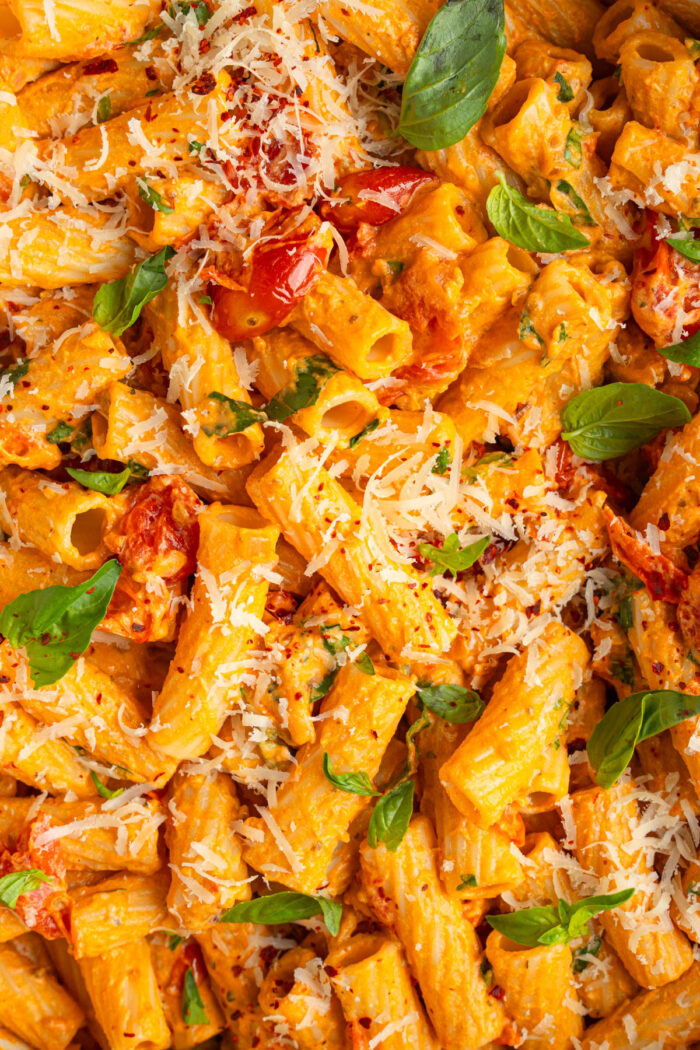 Close up of the creamy tomato pasta with fresh basil and vegan cheese.