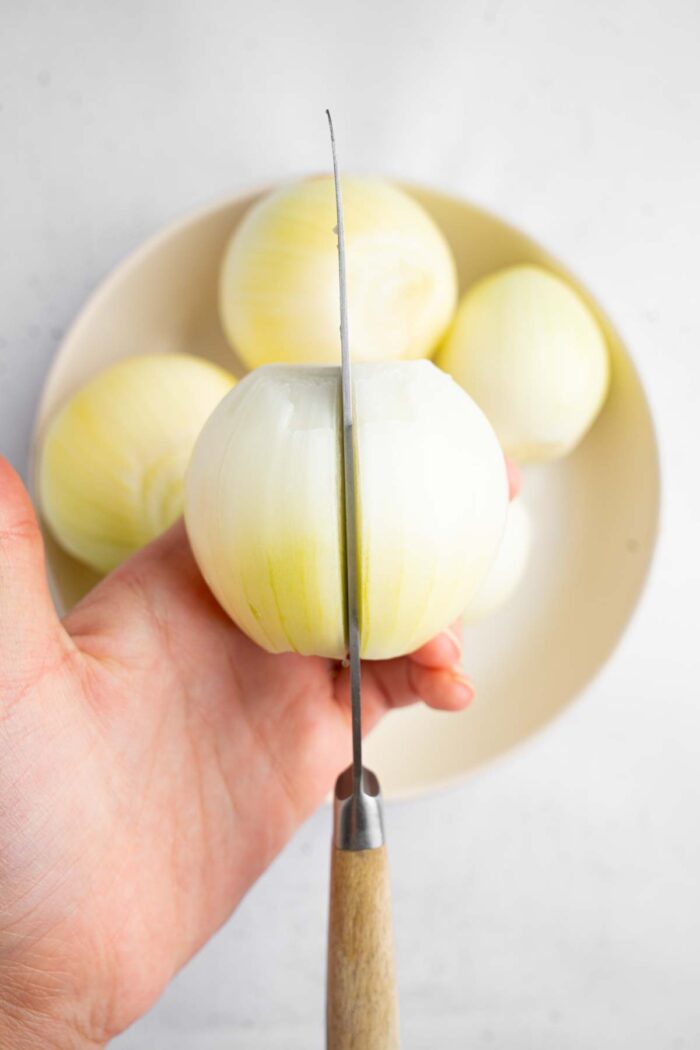A close shot of a large onion being sliced down the middle.