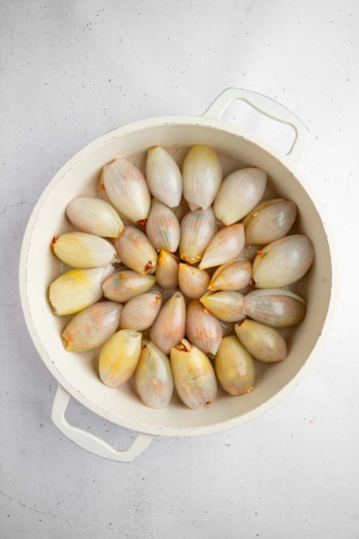 Stuffed onions arranged in a deep dish baking pan in a circular pattern.