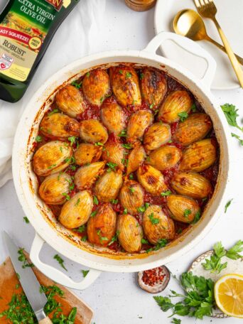 Stuffed onions in the baking pan, served with fresh herbs.