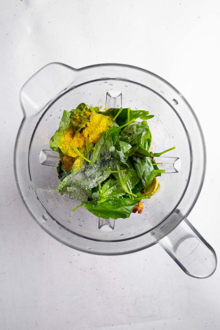 Roasted zucchini mixture in a high-speed blender with fresh basil and seasonings.
