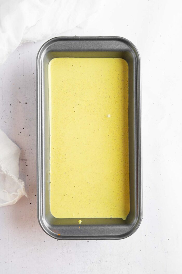 A metal rectangular pan filled with the creamy pistachio mixture.