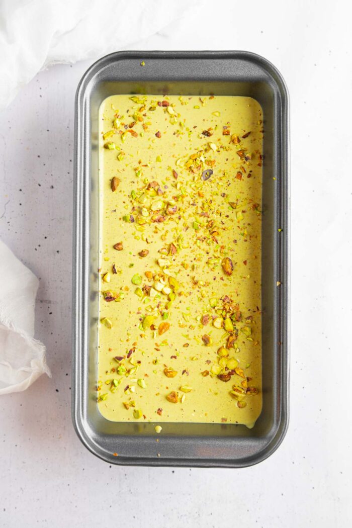 Crushed pistachios spread across the surface of the ice cream base.