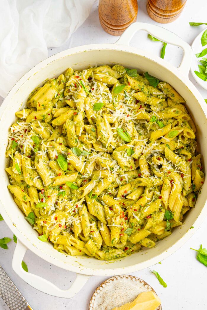 A large pot of zucchini pesto served with fresh basil and vegan parmesan.
