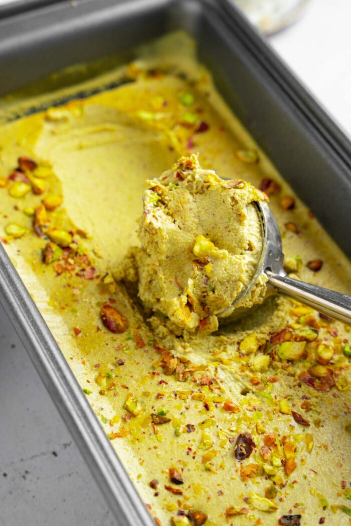 A close up shot of vegan pistachio ice cream being scooped.