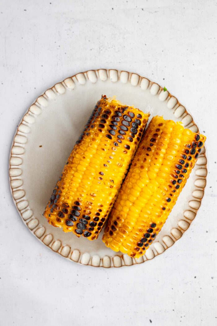 Grilled corn on the cob set on a plate to cool.