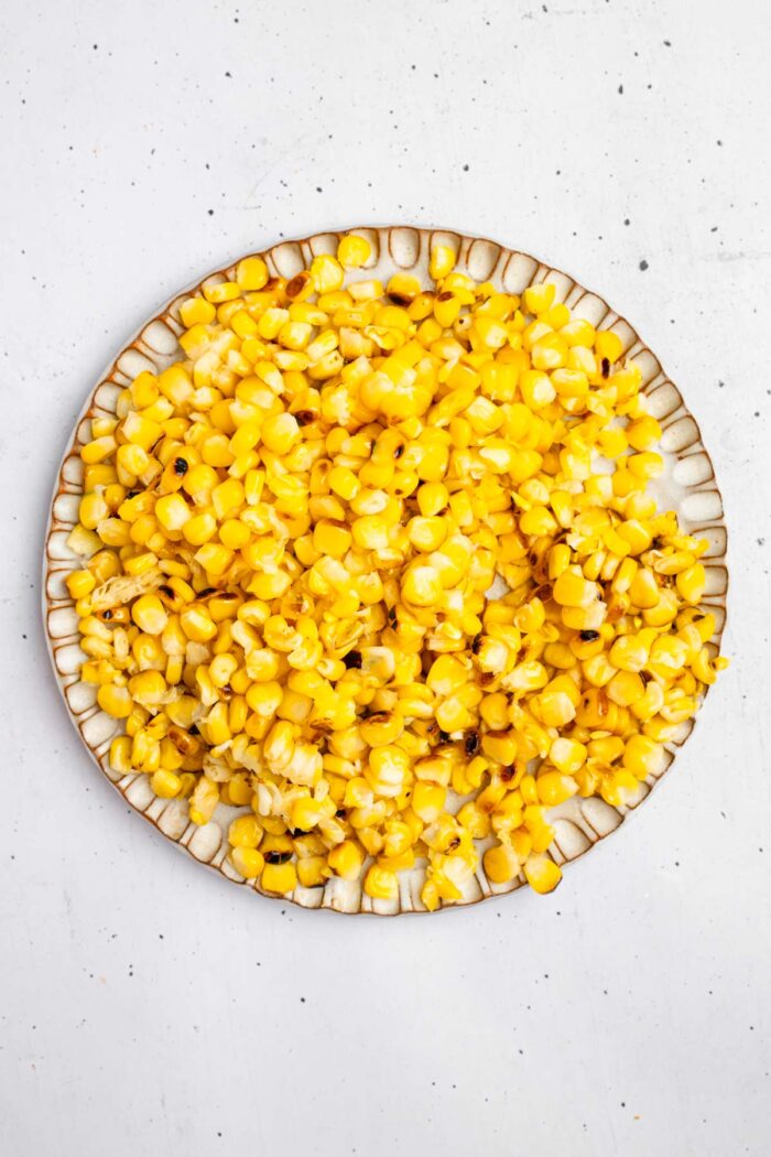 Grilled corn kernels cut off the cobs and set on a plate.