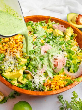 The cilantro lime dressing being drizzled over the avocado and corn salad.