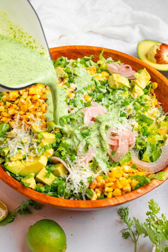 The cilantro lime dressing being drizzled over the avocado and corn salad.