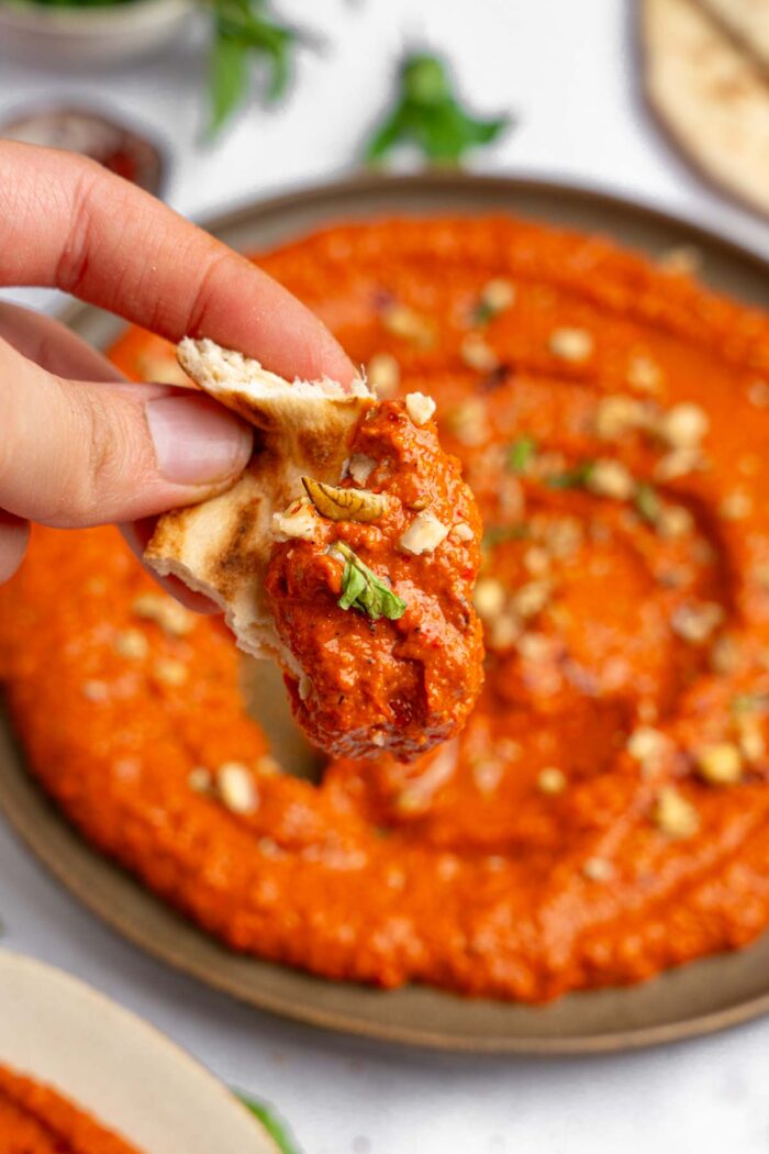 A close up view of the flatbread with a bit of muhammara, with the rest of the roasted red pepper walnut dip visible in the background.