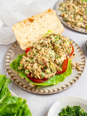 A vegan chicken salad sandwich with the top piece of bread set to the side to show off the vegan chicken salad filling.
