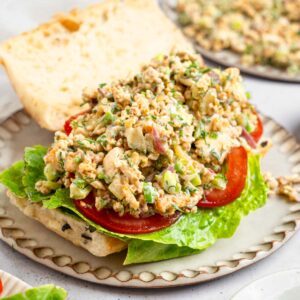 A sandwich open to show the vegan chicken salad filling, along with lettuce and tomato.