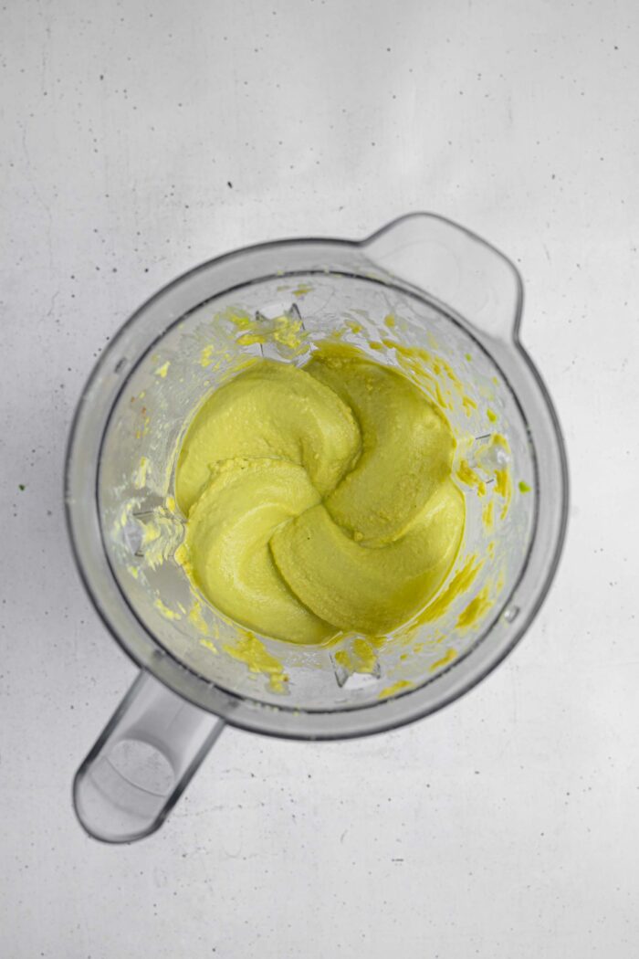 Freshly blended, green avocado hummus, still in the high-speed blender.