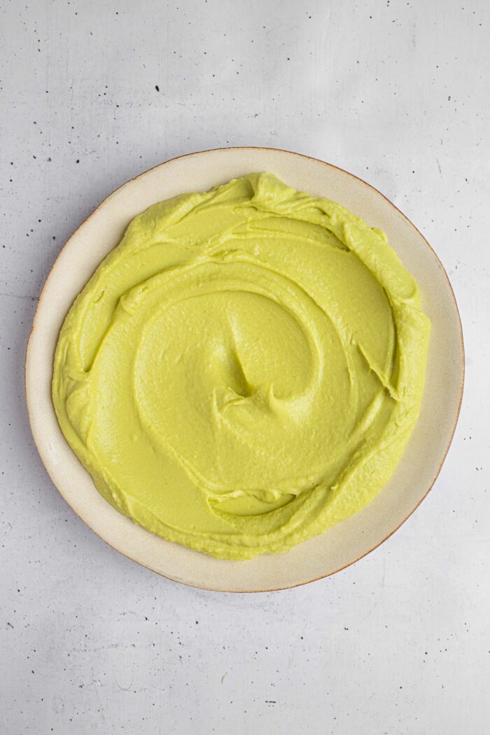 Avocado hummus spread out on a serving plate.