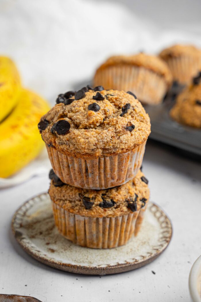 Two banana oatmeal muffins stacked on top of each other on a dessert plate.