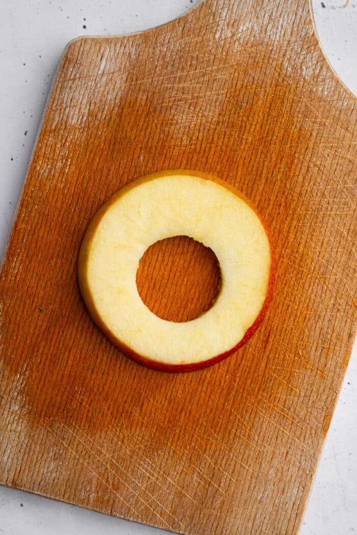 A slice of apple with a round hole cut in the middle.